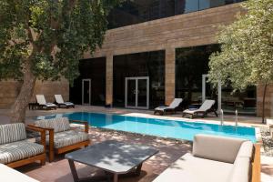 a pool with lounge chairs and a table next to a building at Bristoria Hotel Erbil in Erbil