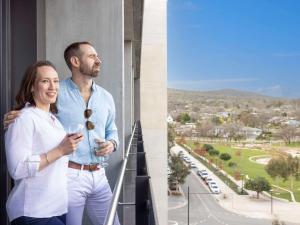 坎培拉的住宿－The Sebel Canberra Campbell，男人和女人站在阳台上喝一杯葡萄酒
