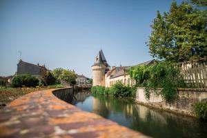 a canal in a town with a tower and buildings at VeniseOuest Hôtellerie de Plein Air in La Ferté-Bernard