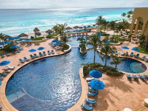 uma vista aérea para uma piscina do resort com cadeiras e guarda-sóis em Kempinski Hotel Cancun em Cancún