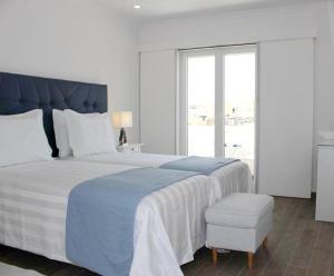 a white bedroom with a large bed and a window at River Inn - Duna Parque Group in Vila Nova de Milfontes