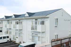 a white apartment building with a white van parked in front at 寄道アパート201-2ベッドルーム布団追加可-最大5名1戸貸切-敷地内駐車場無料 in Kawashima