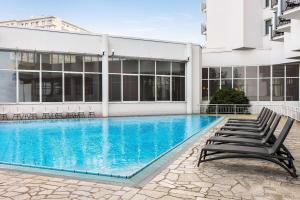 a swimming pool with chairs in front of a building at Vienna House by Wyndham Amber Baltic Miedzyzdroje in Międzyzdroje