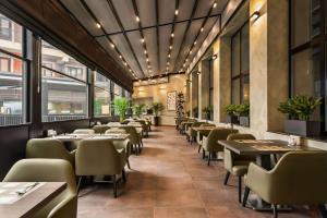 a restaurant with tables and chairs and windows at Ramada Encore by Wyndham Tashkent in Tashkent