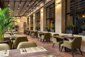 タシュケントにあるRamada Encore by Wyndham Tashkentのテーブルと椅子、植物のあるレストラン