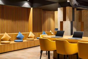 タシュケントにあるRamada Encore by Wyndham Tashkentの黄色い椅子とテーブルにノートパソコン2台が備わるレストラン +37枚の写真