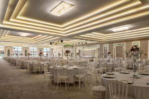 un salón de banquetes con mesas y sillas blancas en Ramada by Wyndham Karacabey, en Bursa
