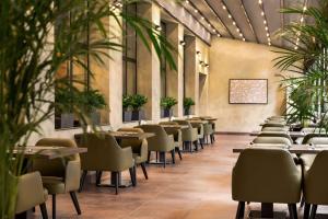 a restaurant with tables and chairs and plants at Ramada Encore by Wyndham Tashkent in Tashkent