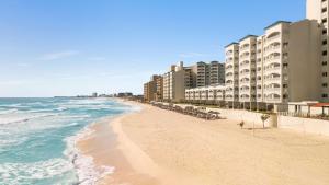 a beach with some buildings and the ocean at Hilton Cancun Mar Caribe All-Inclusive Resort in Cancún