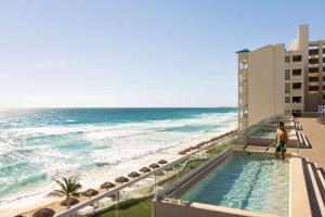 a man standing on the balcony of a hotel overlooking the ocean at Hilton Cancun Mar Caribe All-Inclusive Resort in Cancún