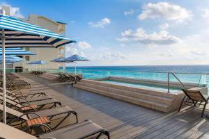 a deck with chairs and a swimming pool and the ocean at Hilton Cancun Mar Caribe All-Inclusive Resort in Cancún