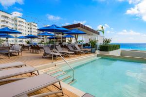 a swimming pool with chairs and umbrellas and the ocean at Hilton Cancun Mar Caribe All-Inclusive Resort in Cancún