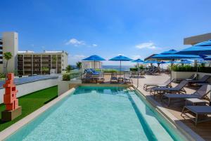 a pool on the roof of a hotel with chairs and umbrellas at Hilton Cancun Mar Caribe All-Inclusive Resort in Cancún