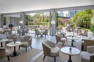 un restaurante con mesas, sillas y ventanas en Kempinski The Boulevard Dubai en Dubái