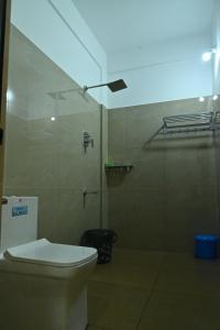 a bathroom with a toilet and a glass shower stall at GR INN in Maraiyūr