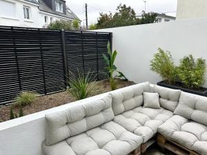 un sofá blanco sentado en un patio junto a una valla en Arz - 2 pièces neuf proche gare de Vannes, en Vannes