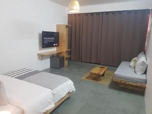 グランベにあるVillas Rocher - Junior Suite 3Bのベッドルーム(ベッド1台、テレビ、ソファ付)