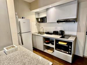 a small kitchen with white cabinets and a refrigerator at The Best in Camba Cua, A metros de la costanera y del centro de la ciudad, ubicacion inmejorable, cerca de la playa, a 2 cuadras parque Cambacua dpto moderno, completamente equipado, con balcon, con todo lo necesario para una estadia comoda y placentera in Corrientes