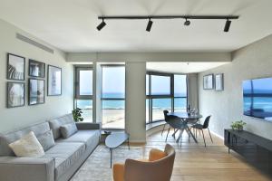 Luxury Suites by Notaly Ariel - Carmel Beach في حيفا: غرفة معيشة مع أريكة وطاولة مع كراسي