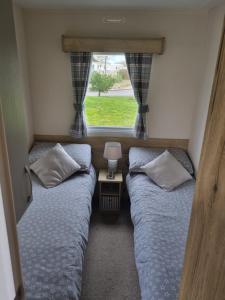 two beds in a small room with a window at Luxury caravan and Tattershall lakes with private hot tub and WiFi in Tattershall