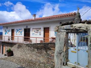 uma pequena casa branca com uma parede de pedra em Vivenda Casa da Fraga em Alijó