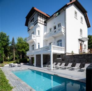 - un grand bâtiment blanc avec une piscine en face dans l'établissement La Villa Concorde, à Gérardmer