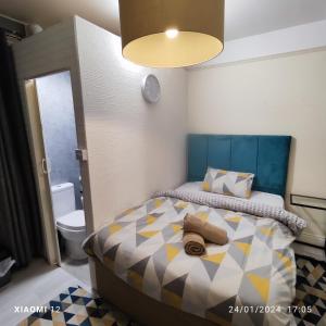 St Lucia lodge Leicester long stays available في ليستر: غرفة نوم صغيرة مع سرير مع اللوح الأمامي الأزرق