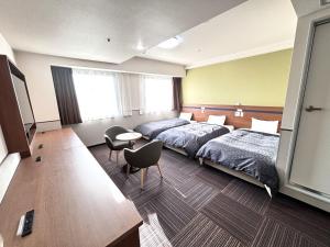 Habitación de hotel con 2 camas, mesa y sillas en Hotel 1-2-3 Kurashiki en Kurashiki