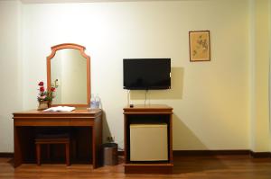 einen Schreibtisch mit einem Spiegel und einen TV an der Wand in der Unterkunft Ranong Garden Hotel in Ranong