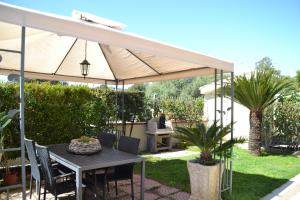 a patio with a table under a white umbrella at Casa delle Conchiglie in Pula