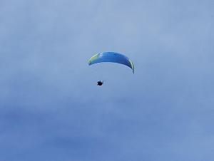 une personne qui vole un parachute bleu dans le ciel dans l'établissement Casa per vacanze degli gnomi, à Challancin