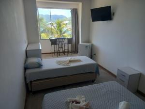 sypialnia z 2 łóżkami i oknem ze stołem w obiekcie Hospedagem Pé Na Areia w mieście Arraial do Cabo