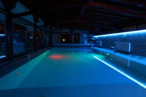una piscina vacía por la noche con luces azules en Barackos Wellness Villa Fót en Fót