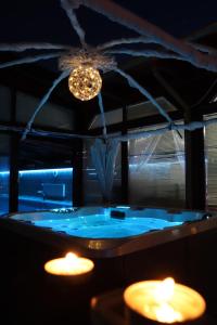 Barackos Wellness Villa Fót في Fót: حمام مع حوض أزرق مع أضواء وشموع
