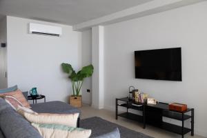 uma sala de estar com um sofá e uma televisão na parede em Luminoso ático en el centro em Santa Cruz de Tenerife