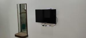 einen Flachbild-TV an einer Wand neben einem Spiegel in der Unterkunft SR RESIDENCY in Chennai
