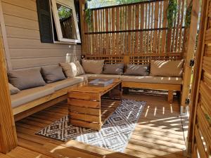 un porche cubierto con sofá y mesa en Camping La Carabasse Vias-Plage - T4 Neuf, Tout Confort !, en Vias