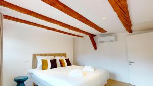 Schlafzimmer mit einem weißen Bett und Holzdecken in der Unterkunft Résidence de l'ancien relais in Colmar