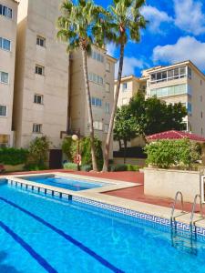 una piscina frente a un edificio con palmeras en Apartment Sunny Albir en Albir