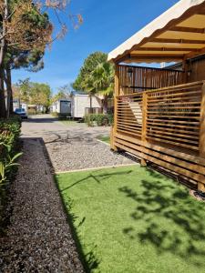 a yard with a wooden fence and green grass at Camping La Carabasse Vias-Plage - T4 Neuf, Tout Confort ! in Vias