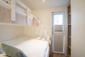 a bedroom with a bunk bed and a window at Ostseecamp Lübecker Bucht Ferienhaus "JU-LI" mit kostenlosen Saunazugang in Scharbeutz