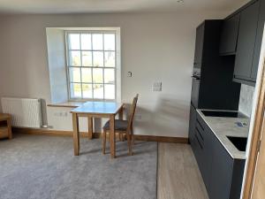 uma pequena cozinha com uma mesa e uma janela em Grindal - Executive Apartment Hotel em St Bees