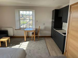 a room with a table and a kitchen with a window at Grindal - Executive Apartment Hotel in St Bees