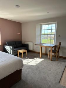 a bedroom with a bed and a couch and a table at Grindal - Executive Apartment Hotel in St Bees