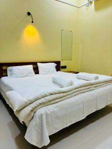 een groot bed met witte lakens en kussens in een kamer bij Kihim Paradise Beach & Resort in Alībāg