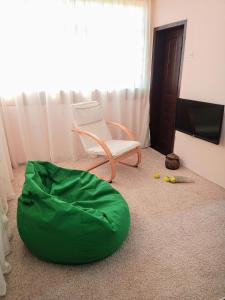 ein Wohnzimmer mit einem Stuhl und einem grünen Sitzsack in der Unterkunft Kuća iz zavičaja in Kuršumlija