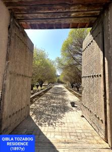 ein offenes Tor zu einer Straße mit Bäumen in der Unterkunft QiBLA TOZABOG in Xiva