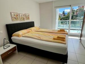 ein Schlafzimmer mit einem großen Bett und einem großen Fenster in der Unterkunft Residenza Monte Verità, apt nr 10 in Ascona