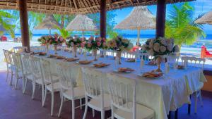 a long table with white chairs and flowers on a beach at Kijiji Beach Resort in Dar es Salaam