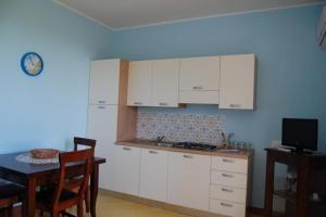 a kitchen with white cabinets and a table and a tv at Apartment mit Terrasse - b57363 in Acireale